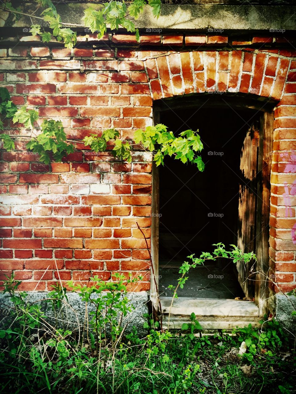 Invitation. Open door to abandoned brick building