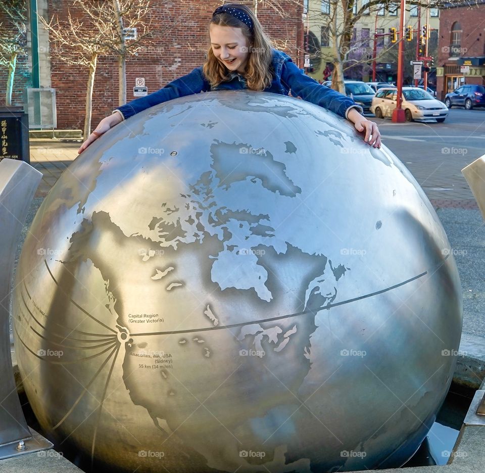 Girl hugging a giant metal globe