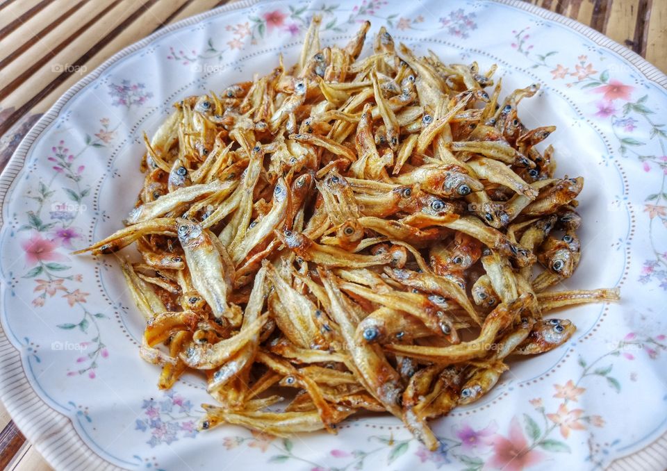 fried fish in white dish on bamboo table