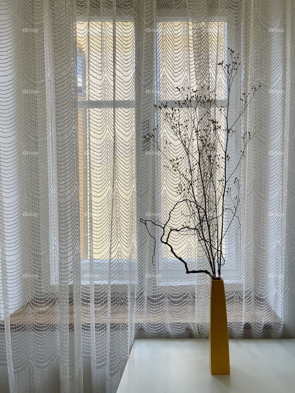 Yellow vase with dry flowers on the window background 