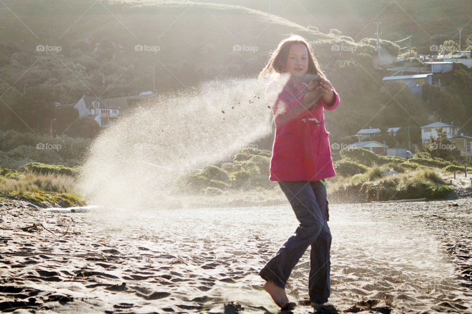 Girl throwing sand at beach