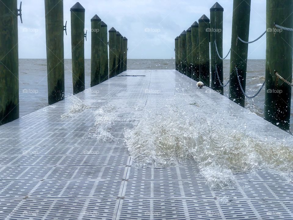 Strong wind high tide heavy surf splashing through metal dock on Gulf of Mexico 
