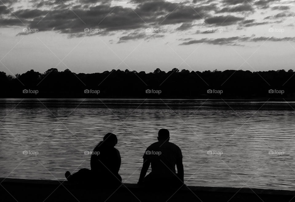 Black and White Sunset photo. A couple sitting on the dock of the bay having a lively discussion.