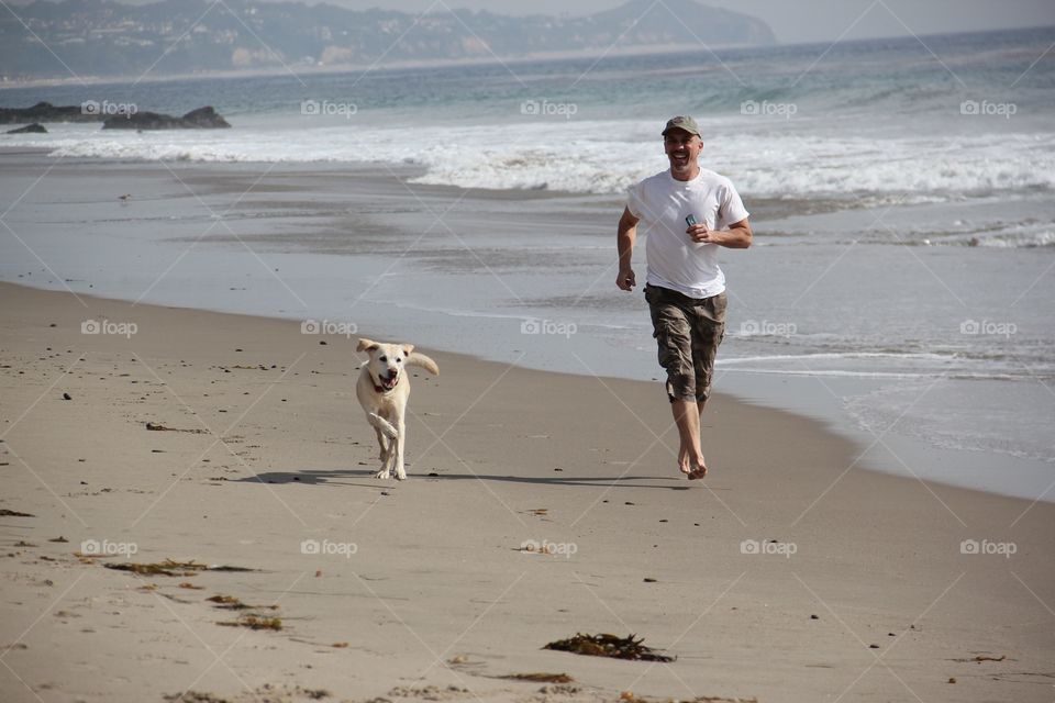 Man running with his dog at beach