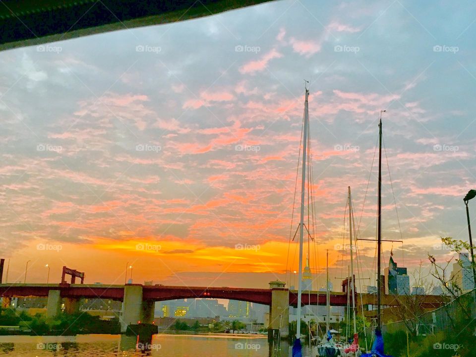 The Pulaski Bridge at Newtown Creek in Long Island City, Queens, NY with a dramatic orange gold cloud formation in the evening skies above it. Photographed in 2019. Hypnotic Productions