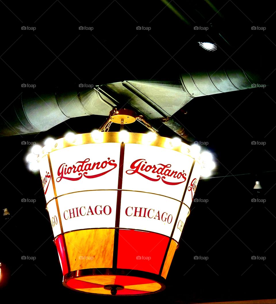 Illuminating red, orange, & white stained glass hanging lamp of legendary Giordanos Chicago style deep dish pizzeria in downtown Chicago.