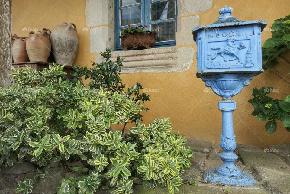 Old blue mailbox near a yellow house