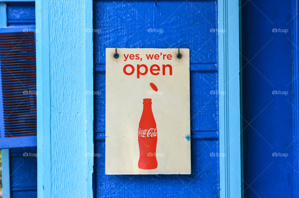 Coca cola business open sign against a bright blue wall