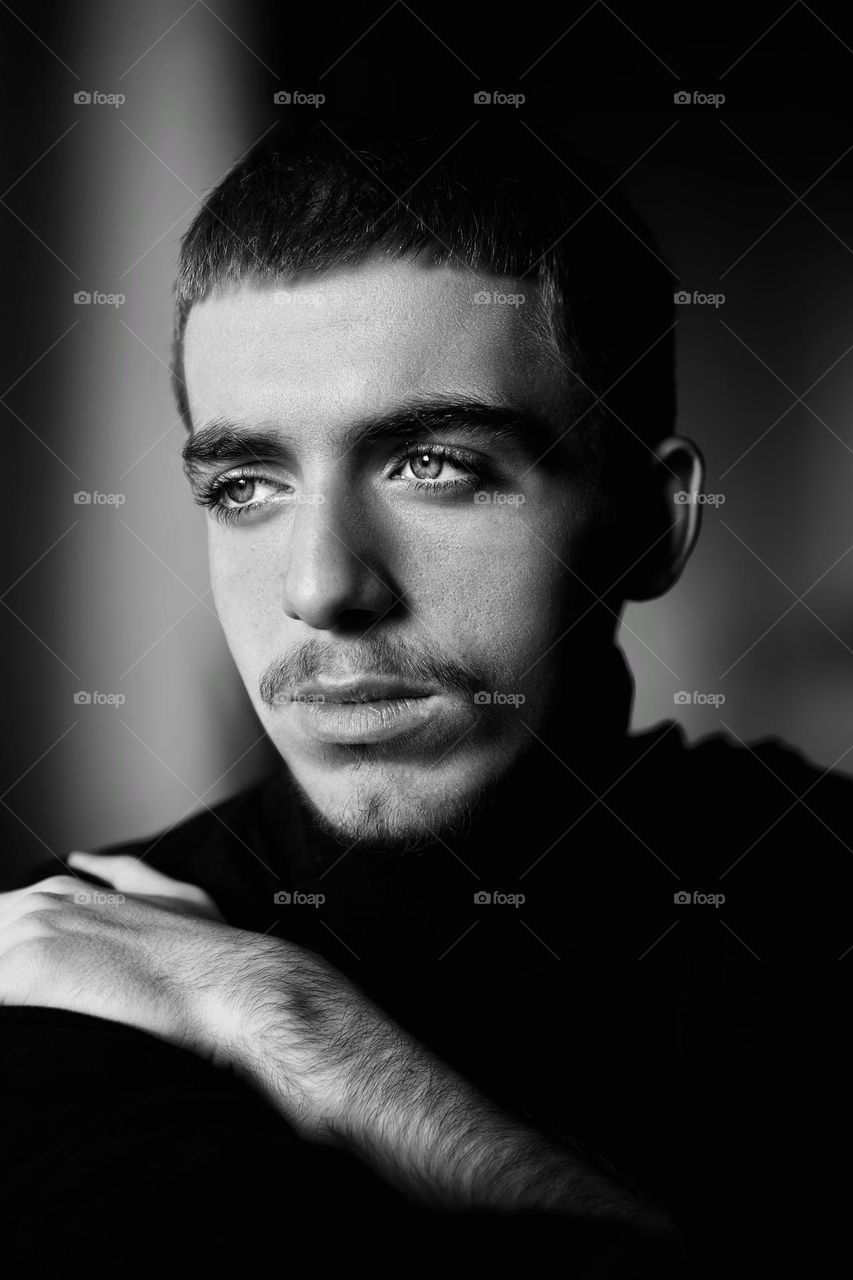 Close-up of thoughtful young man looking away against wall.