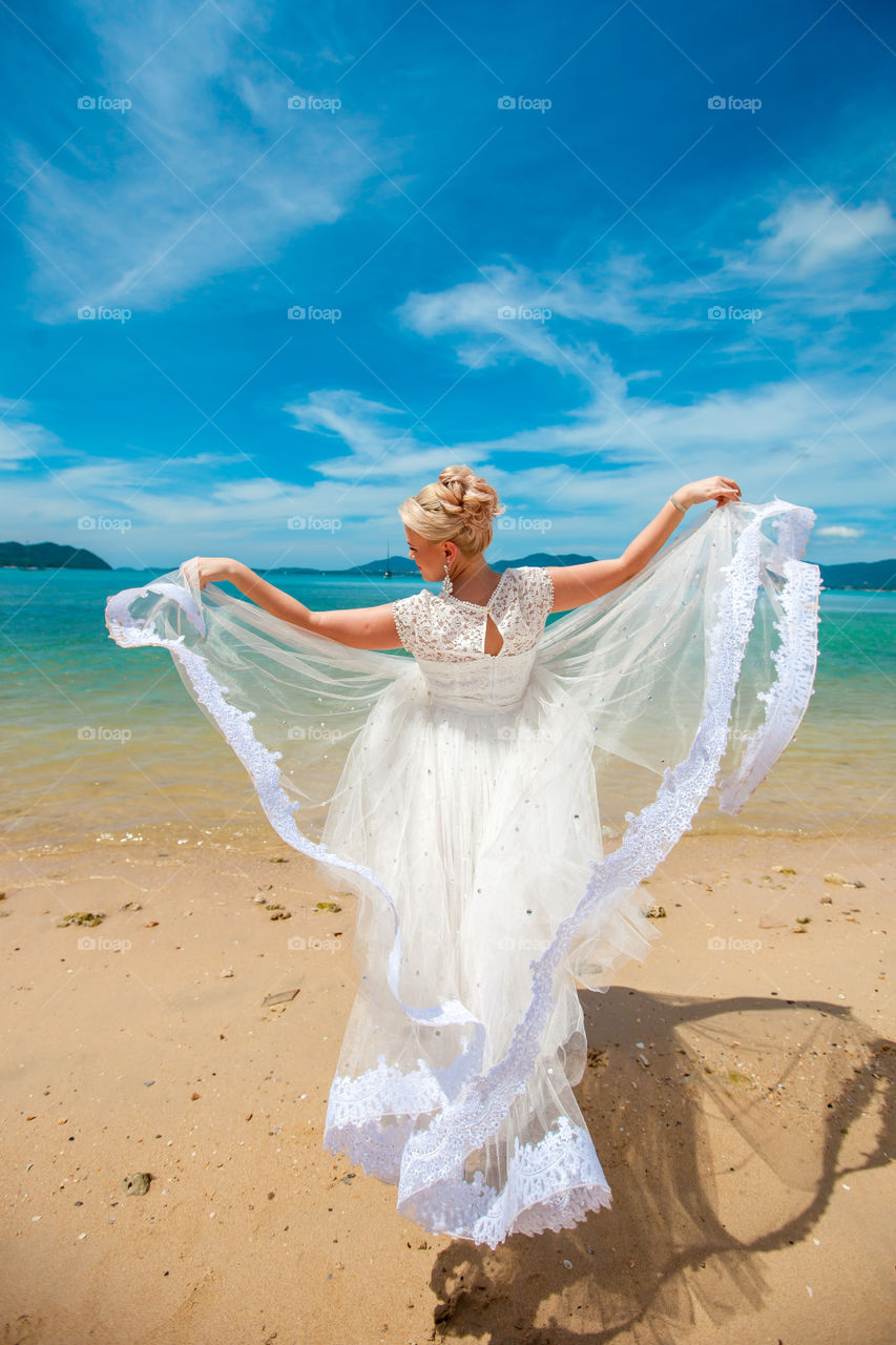 girl on the beach in the air white wedding dress