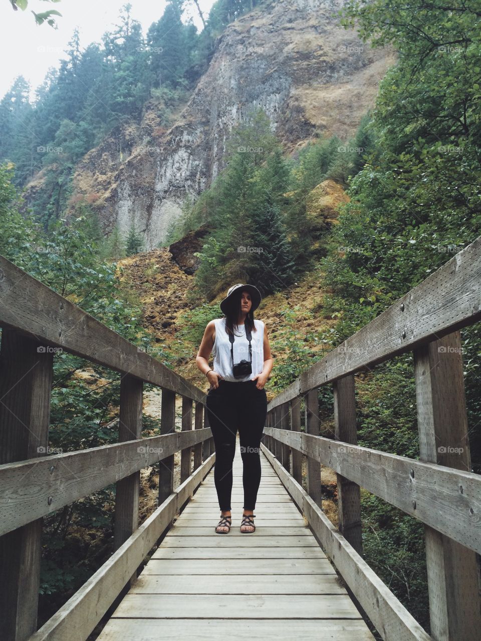 Hipster girl on a bridge . Young stylish photographer girl out on the trail 