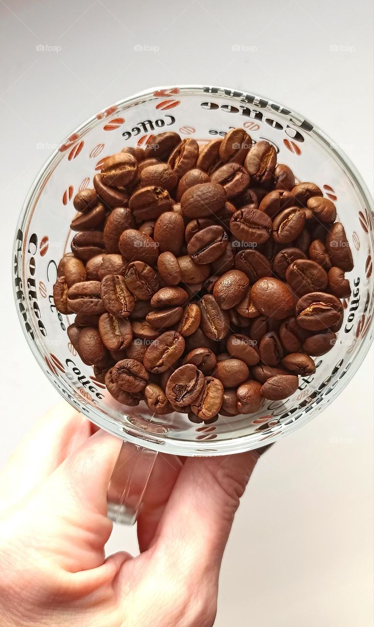 cup of coffee beans in the hand on a white background, top view, love coffee