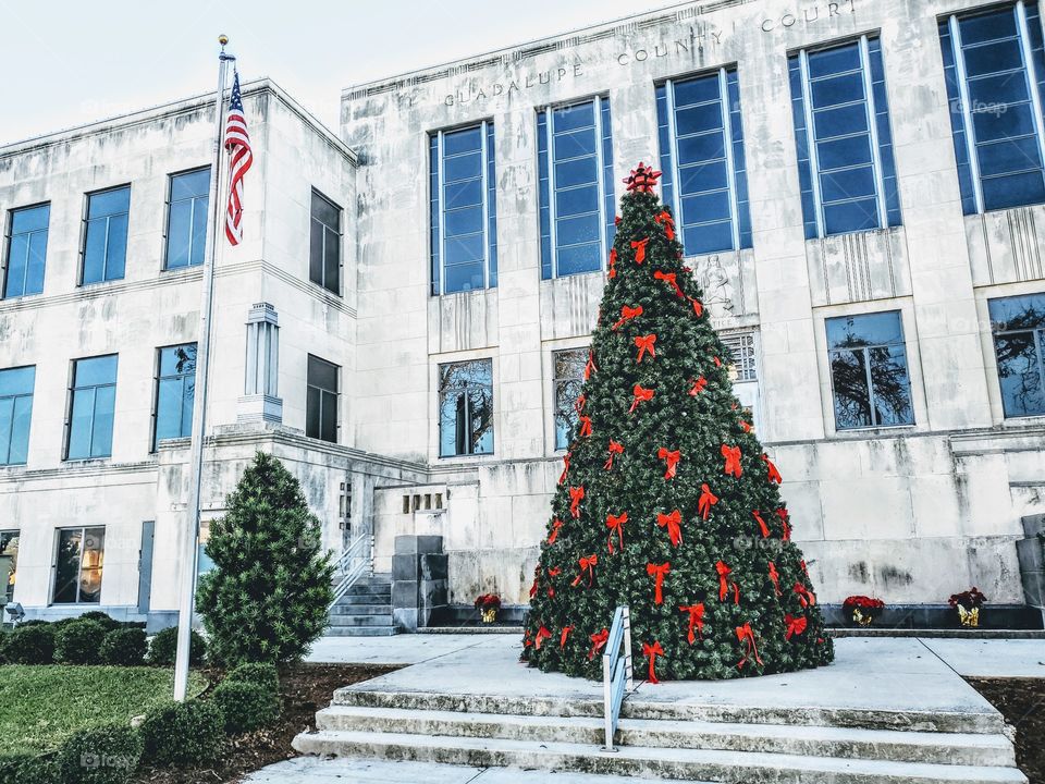 Christmas tree in front of courthouse next to flag pole with US American flag