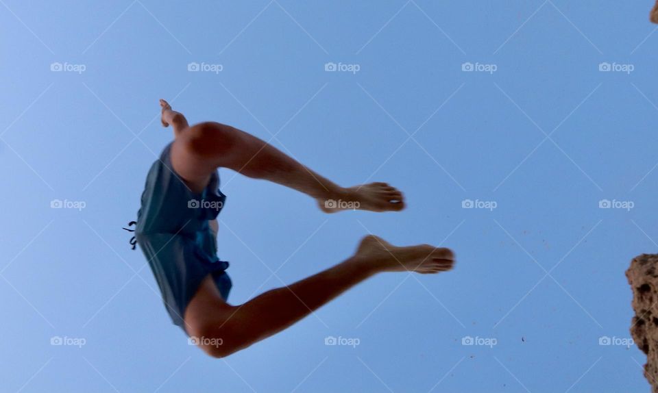 Kid jump from the cliff view from below 