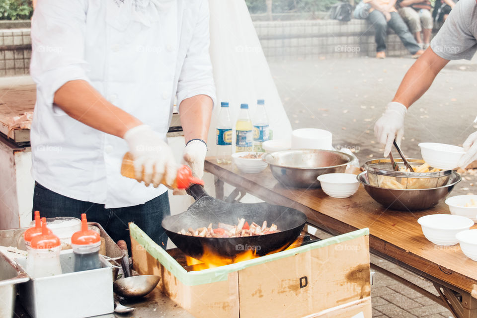 men cooking Peruvian food at street market stall at summer festival