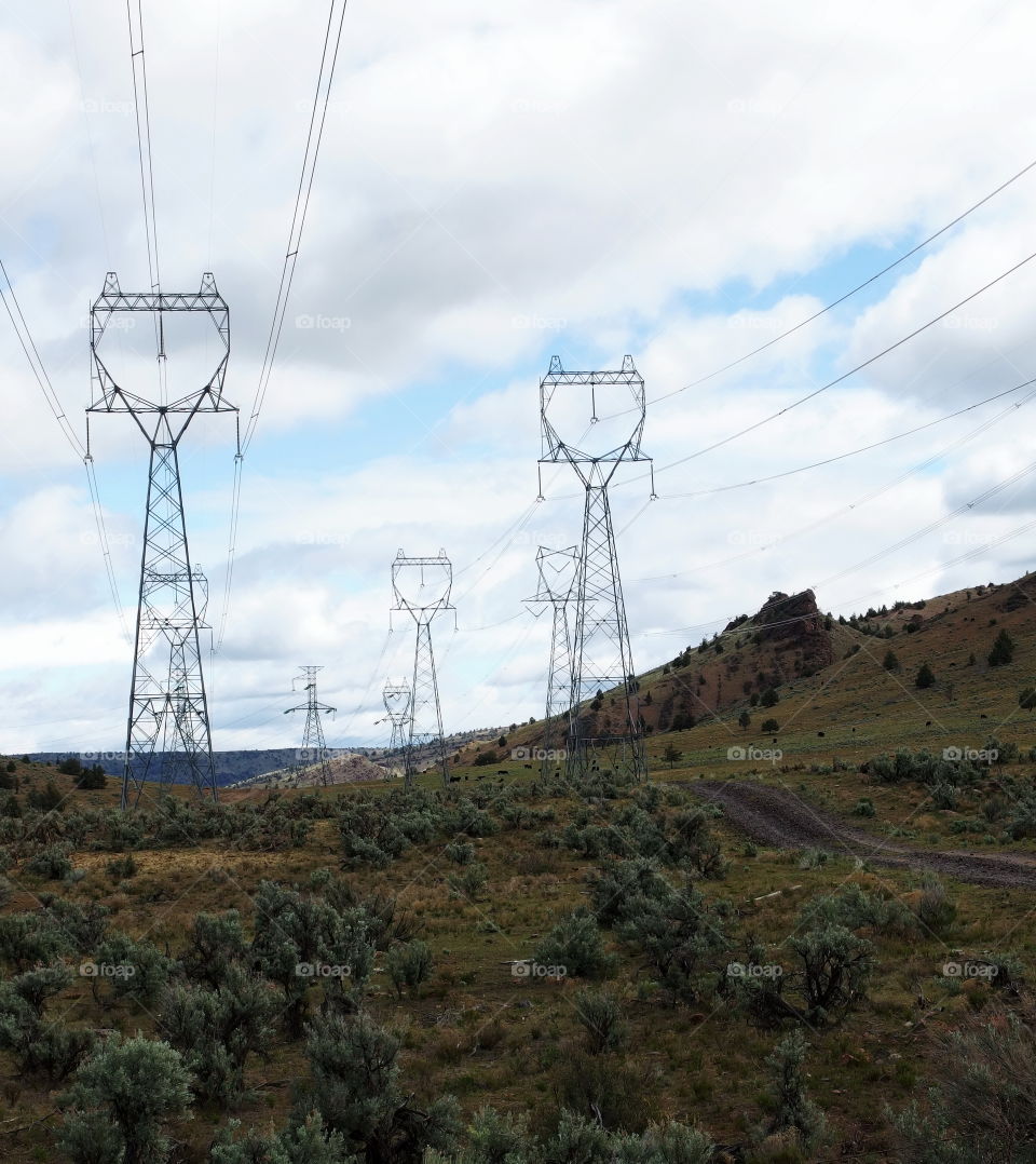 A backroad through rows of towering power lines in the rural countryside in Central Oregon on a nice day. 