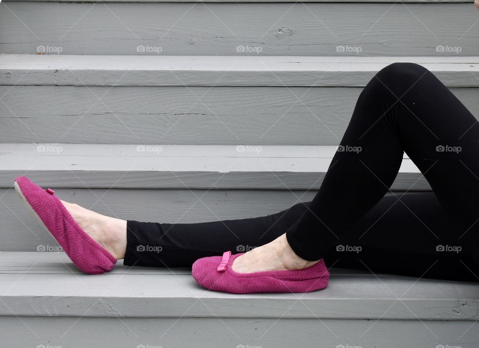 Woman wearing Isotoner slippers while sitting on the stairs 