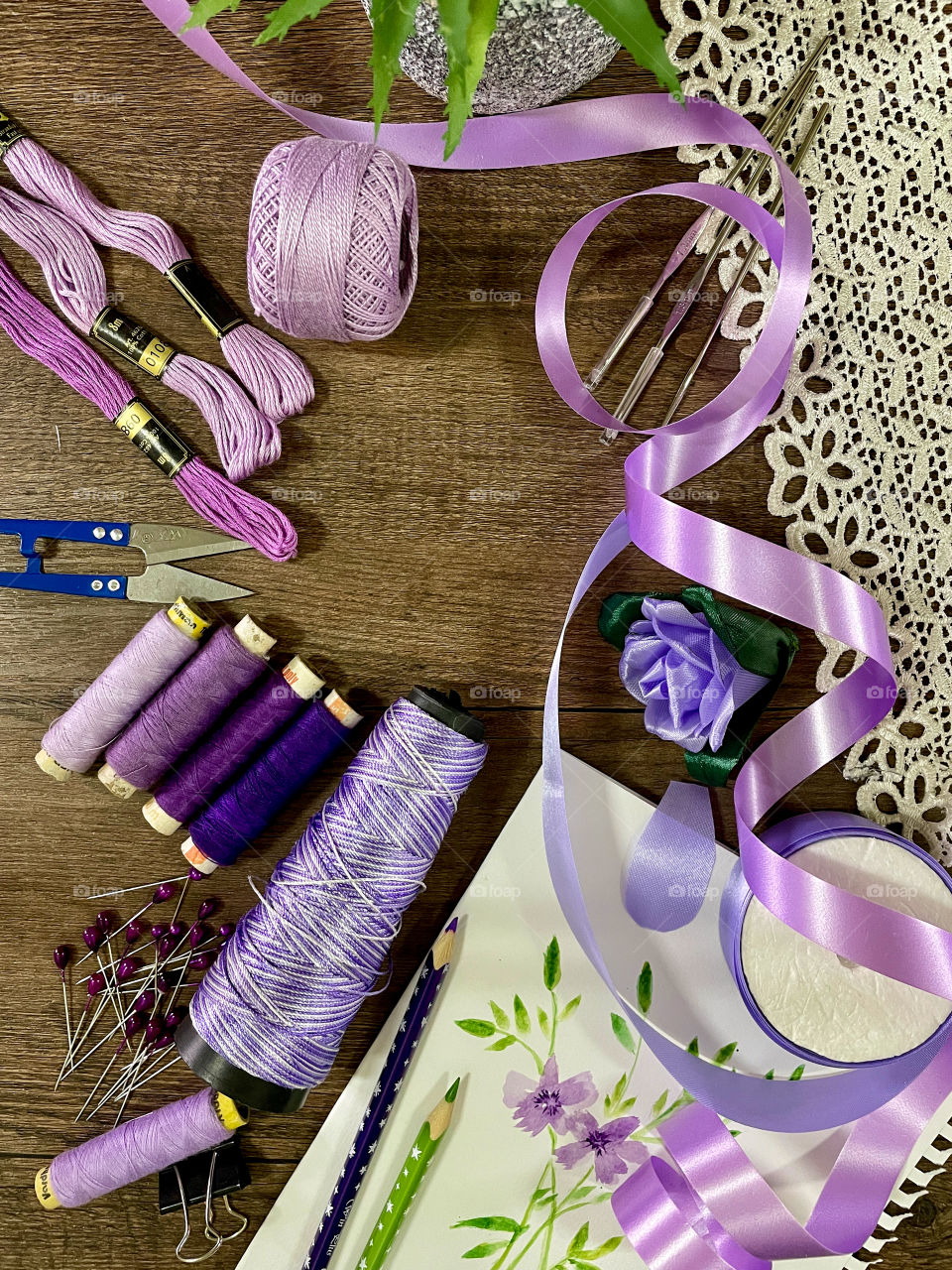Your best flat lays. Embroidery threads ,satin ribbons, drawing pencils , lace satin ribbons are on a wooden table . Craft and art based theme concept 