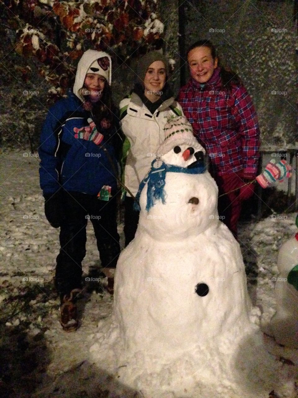 Snowman!  . Three friends building a snowman at night after the first snowfall.
