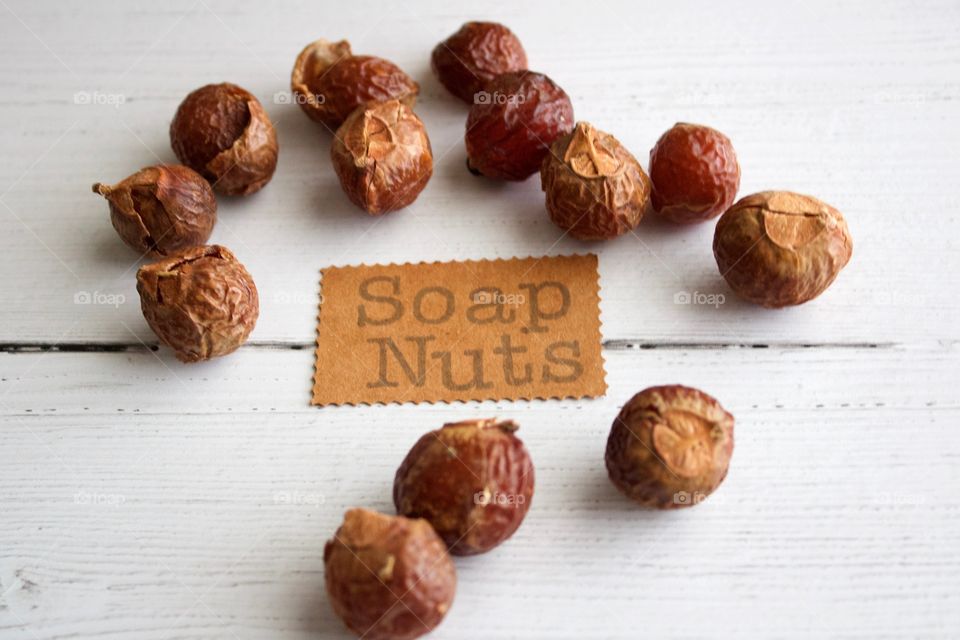 Soap nuts or soap berries on weathered white wooden background with identification placard in natural light