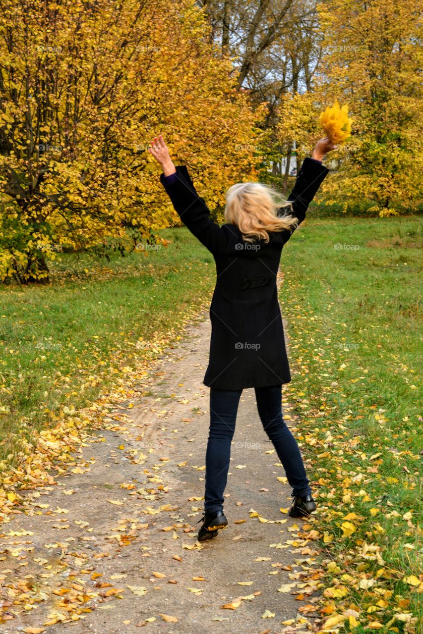 girl with yellow leaves in autumn park beautiful landscape social distance