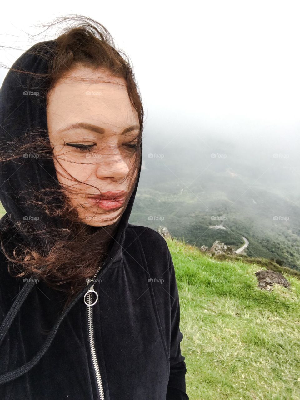 Young woman standing at hill in foggy weather