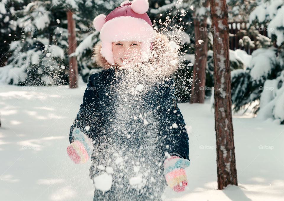 Little girl playing in snow at park