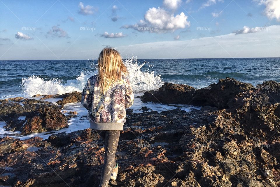 Girl walking on rocks by the sea