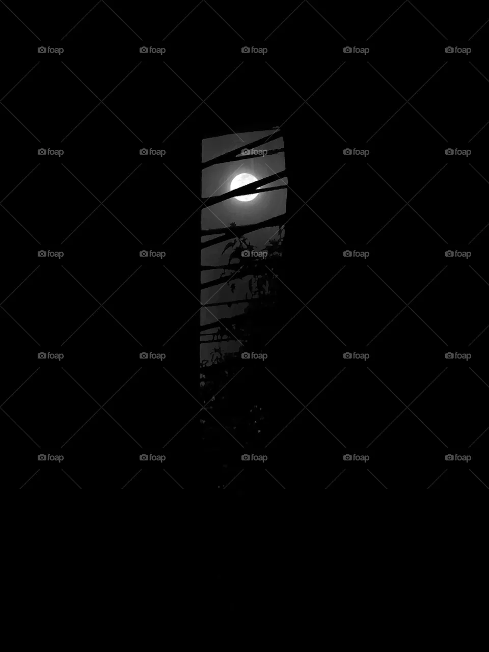 Full moon seen through the window from completely dark room.