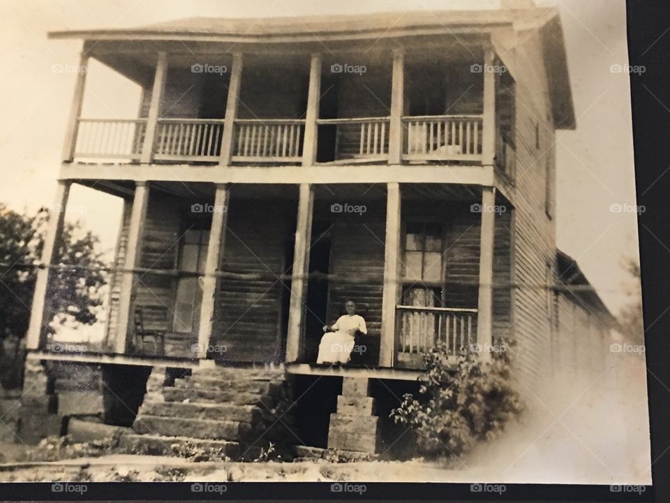 Picture of a picture with a woman in a rocking chair on the front porch. Waiting 
