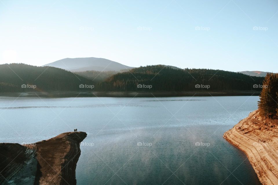 tiny people sitting near a lake