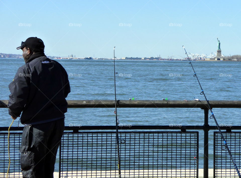 fisherman in fronte of the statue of liberty newyork