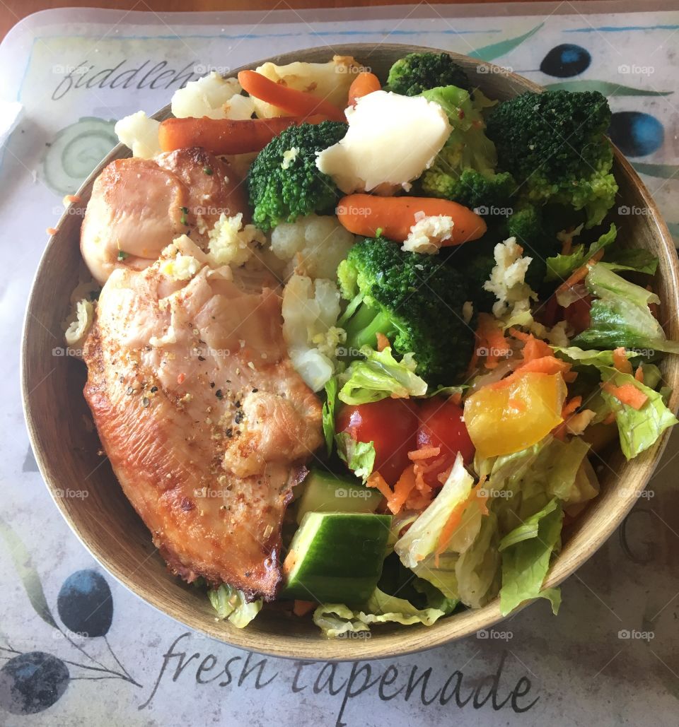 A salad bowl topped with healthy vegetables and oven-roasted chicken.