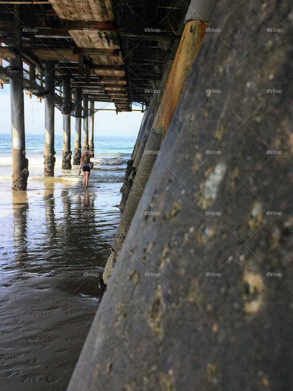 Person walking to the beach under a pier, Santa Monica Pier, California