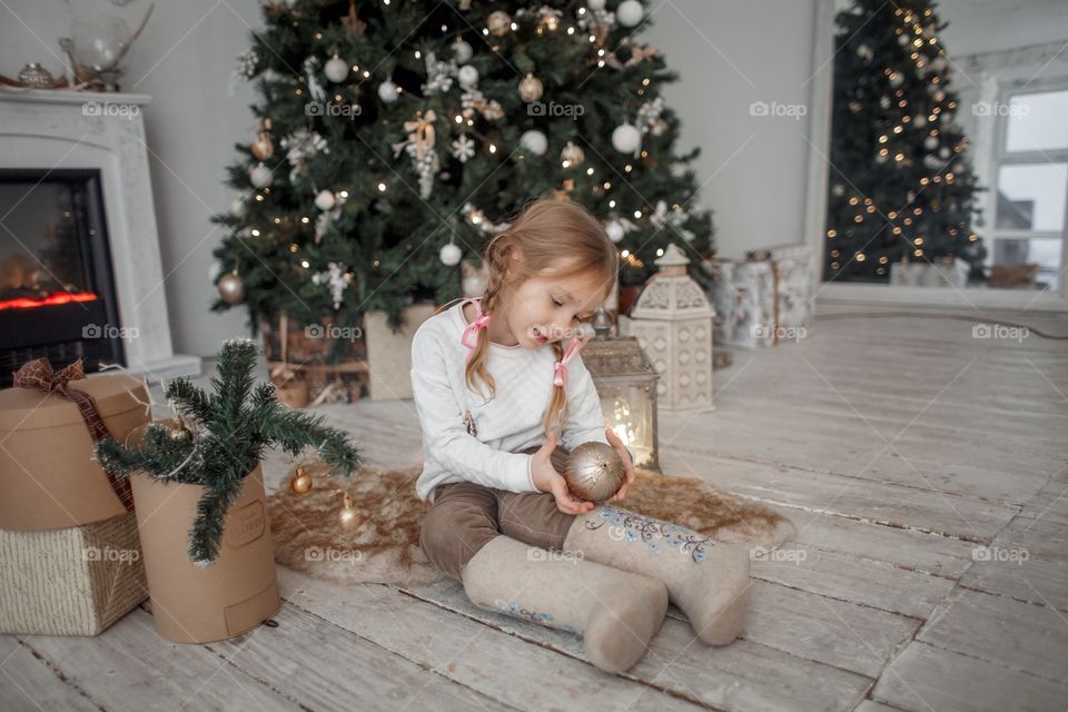 Little girl near Christmas tree at home