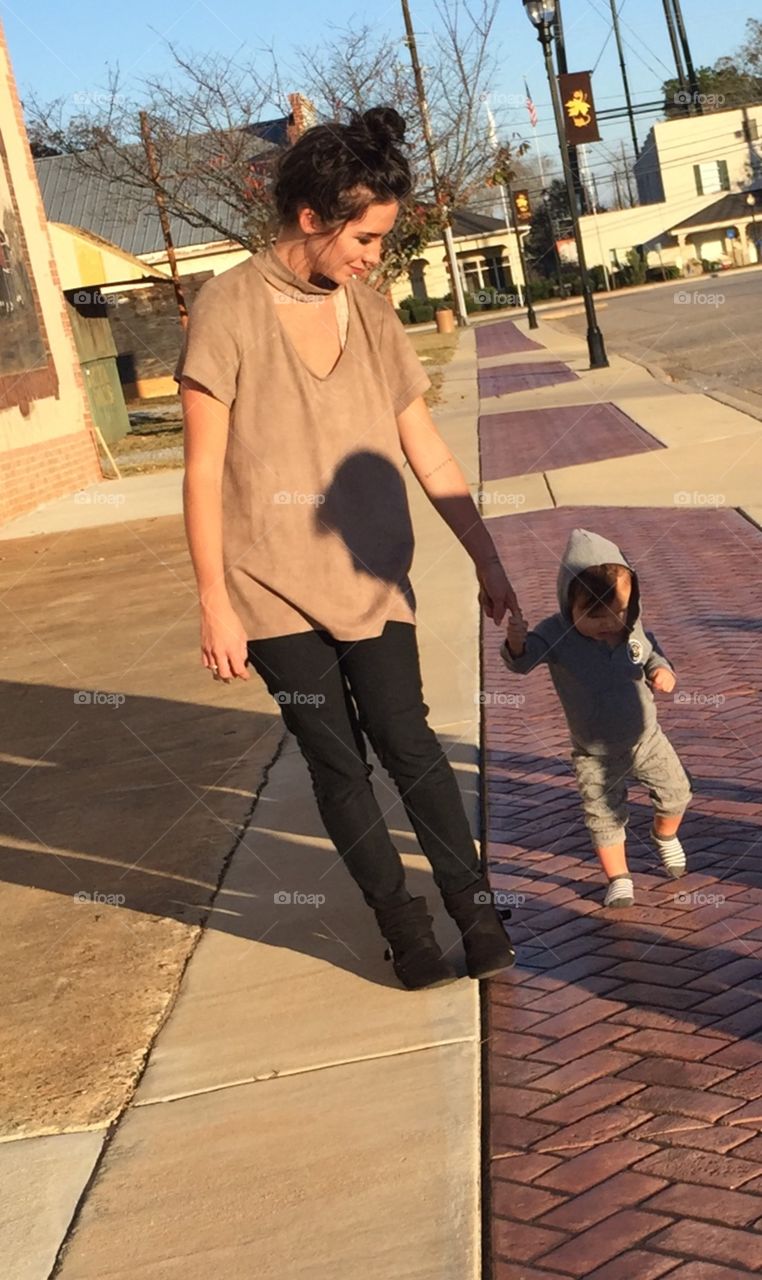 Mother and son walking down the brick town sidewalk. 