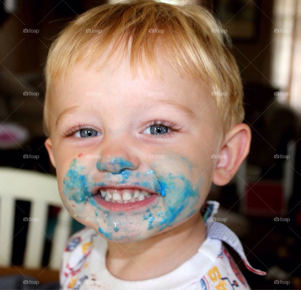 Blue Face Cheesin' . Cute little toddler, with his face covered in blue frosting, smiling big for the camera. 