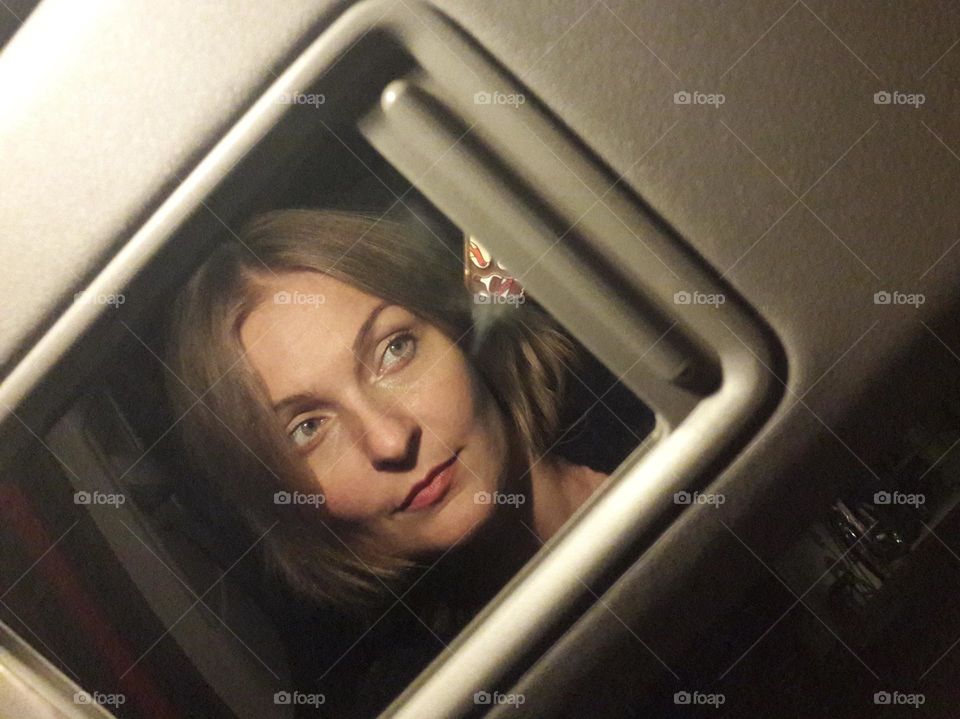 Reflection of a woman in a car interior mirror 