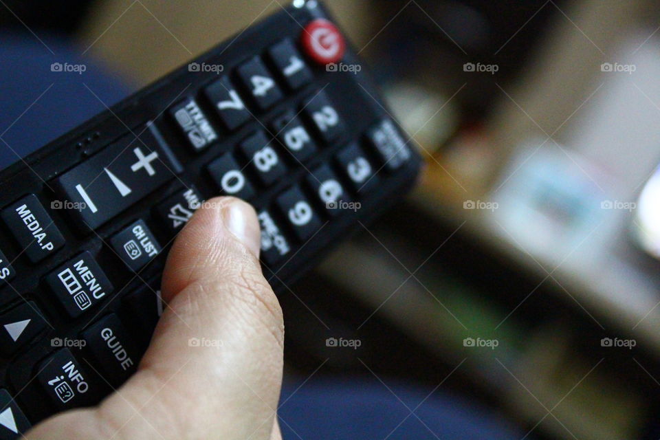 Human hand holding the TV remote focused macro