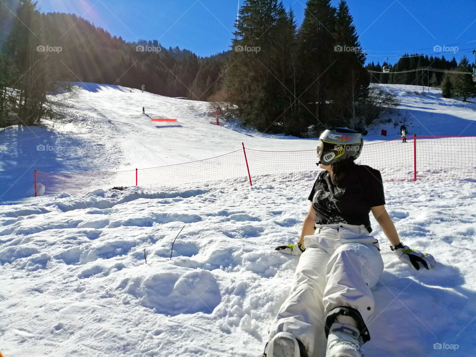 Girl sitting on the snow in a ski resort