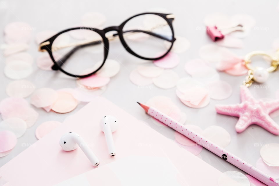 reading glasses, wireless headphones, notebook, pencil, confetti lying on gray concrete background 