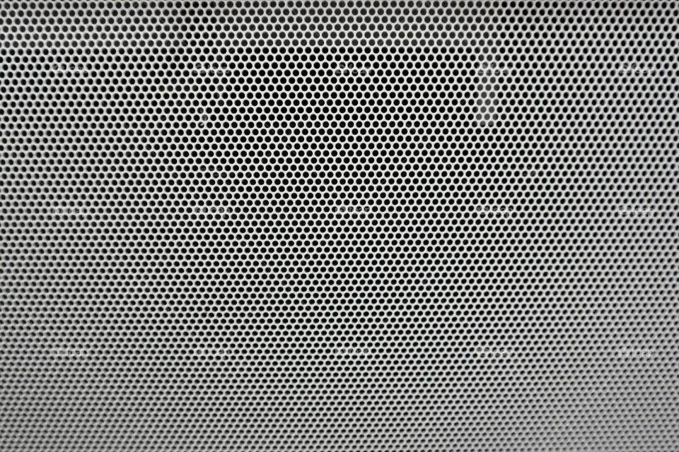 White texture mesh grille design on black background with circular holes