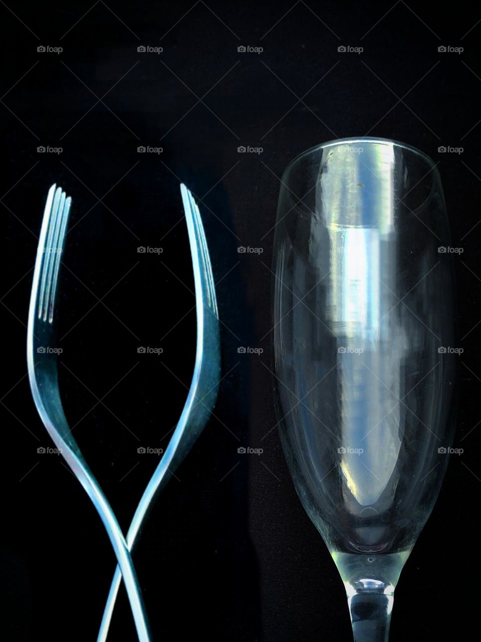 Creative forks. Two metal forks are stacked in the shape of a wine glass. Next to it is a wine glass for comparison. Background black