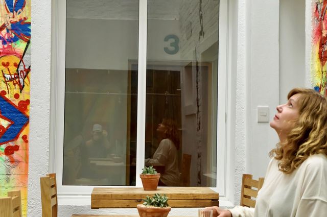 A beautiful woman looks up while her reflection is captured in a window.