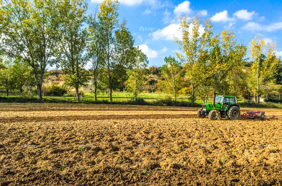 Tractor Ploughs Field In A Beautiful Rural Landscape

