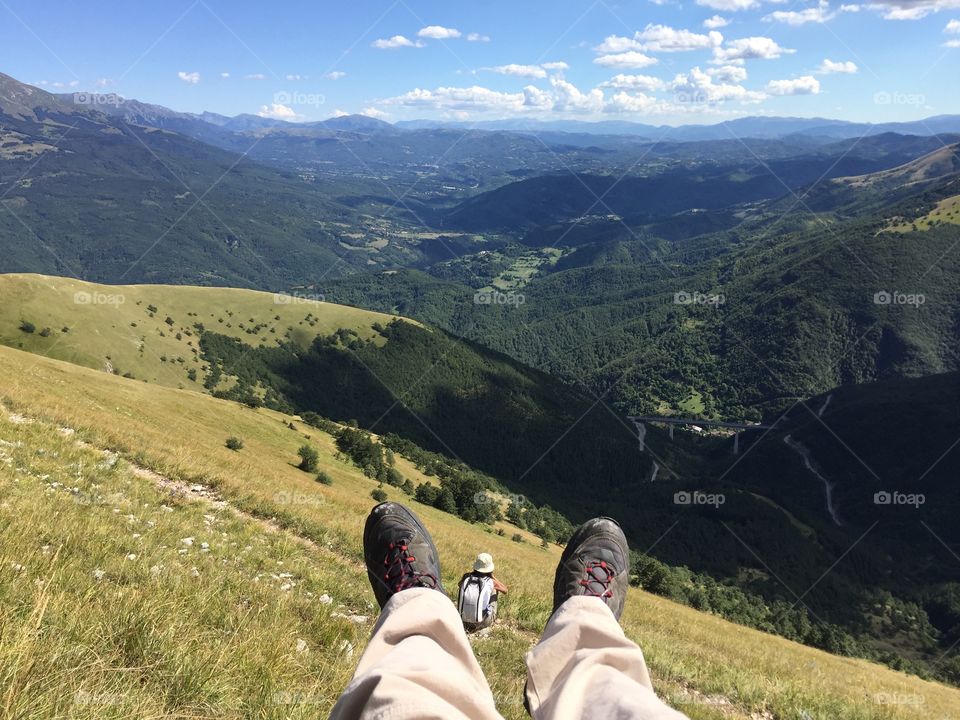 Feet above in high mountain with a small person sitting between