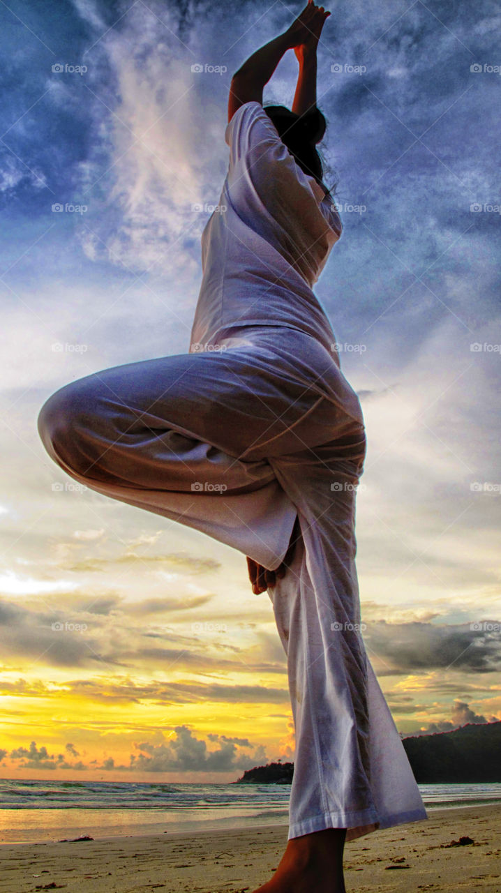 Yoga and beautiful sky. lady posing during yoga session at the beach on a sunny day