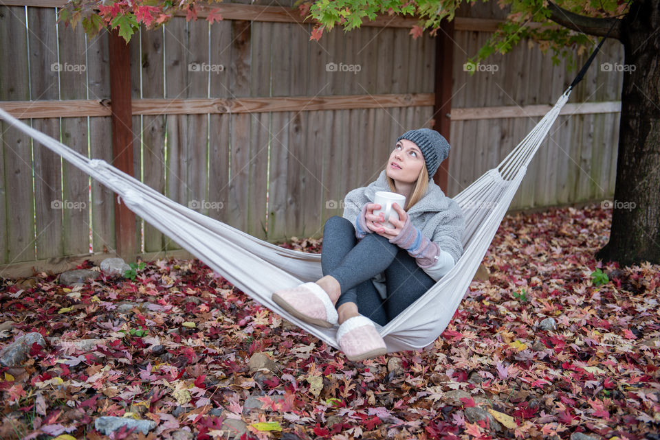 Young millennial woman sitting in a hammock in the fall