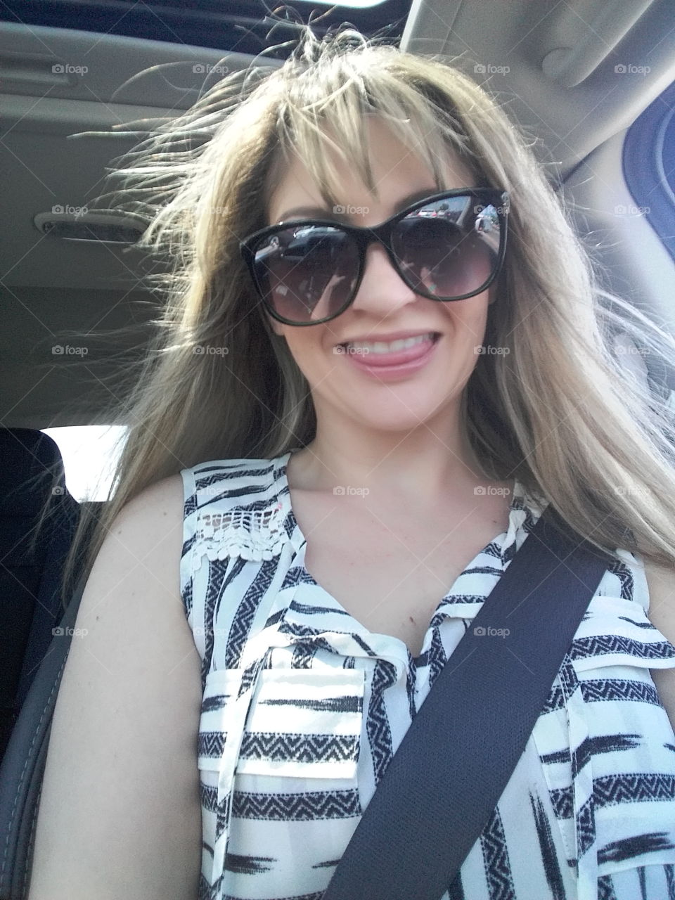 Woman sitting in car wearing sunglasses