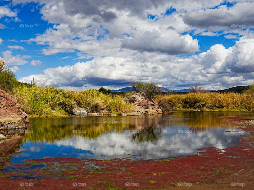 Clouds fill the sky over a pond with deep colorful reflections